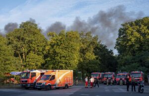 Fire engines and ambulances stand on Kronprinzessinnen road at the Grunewald forest in Berlin, Germany, Thursday, Aug. 4, 2022. A large fire has broke out in one of Berlin’s biggest forests triggered by several explosions that took place on a blasting site inside the forest leading to canceled public transportation and the closure of several roads. Christophe Gateau/dpa via AP)