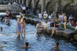 FILE – Children cool themselves in the water of the Neglinnaya river enjoying the end of a hot day near the Kremlin Wall, in Moscow, Russia, July 3, 2022. Six months after Russia sent troops into Ukraine, there’s little sign of the conflict on Moscow’s streets and the capital’s residents seem unconcerned about the economic and political sanctions by Western countries. (AP Photo/Alexander Zemlianichenko, File)