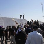 Supporters of Shiite cleric Muqtada al-Sadr try to remove concrete barriers in the Green Zone area of Baghdad, Iraq, Monday, Aug. 29, 2022. (AP Photo/Hadi Mizban)