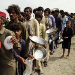 Flood affected people stand in a long line with utensils to get food distributed by Pakistani Army troops in a flood-hit area in Rajanpur, district of Punjab, Pakistan, Saturday, Aug. 27, 2022. Officials say flash floods triggered by heavy monsoon rains across much of Pakistan have killed nearly 1,000 people and displaced thousands more since mid-June. (AP Photo/Asim Tanveer)