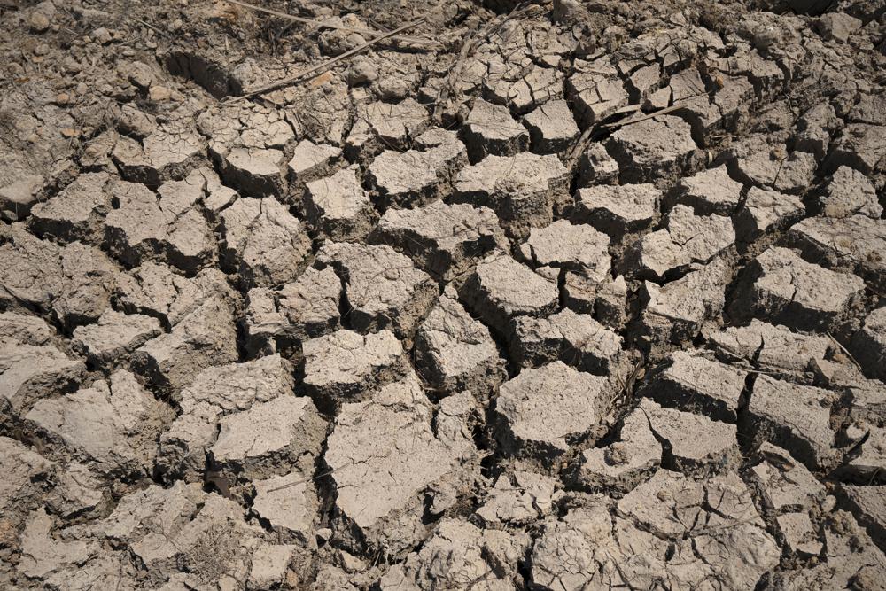 FILE – Cracked dry mud is seen in a community reservoir that ran nearly empty after its retaining wall started to leak and hot weather and drought conditions accelerated the loss of water Longquan village in southwestern China’s Chongqing Municipality, Saturday, Aug. 20, 2022. The very landscape of Chongqing, a megacity that also takes in surrounding farmland and steep and picturesque mountains, has been transformed by an unusually long and intense heat wave and an accompanying drought. (AP Photo/Mark Schiefelbein, File)