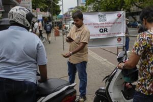 A worker scans a QR code before pumping gas to a vehicle at a fuel station in Colombo, Sri Lanka, Tuesday, Aug. 2, 2022. Sri Lanka introduced fuel distribution using the QR code Monday as part of implementing a weekly quota for motorists. (AP Photo/Eranga Jayawardena)