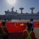 Sri Lankan port workers hold a Chinese national flag to welcome Chinese research ship Yuan Wang 5 as it arrives in Hambantota International Port in Hambantota, Sri Lanka, Tuesday, Aug. 16, 2022. The ship was originally set to arrive Aug. 11 but the port call was deferred due to apparent security concerns raised by India. (AP Photo/Eranga Jayawardena)