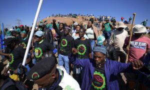 Mine workers sing as they wait for the start of commemoration ceremonies near Marikana in Rustenburg, South Africa, Tuesday, Aug. 16, 2022. South Africa marks on Tuesday 10 years since the Marikana massacre, where 44 people were killed during a mine strike at a platinum mine near Rustenburg, North West province in August 2012. (AP Photo/Themba Hadebe)