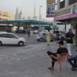 A man laughs while drinking tea as another passes holding karak in Dubai, United Arab Emirates, Wednesday, Aug. 24, 2022. Karak is the informal national drink of the United Arab Emirates, long priced at just 1 dirham, a bit less than 30 U.S. cents. But now, as supply chain shortages and Russia’s war on Ukraine lead to price spikes across the world, Dubai’s tea sellers are bumping up prices to 1.50 dirhams, or just over 40 cents. That’s a blow to migrant workers who depend on the drink as a daily ritual offering respite and fuel. (AP Photo/Jon Gambrell)