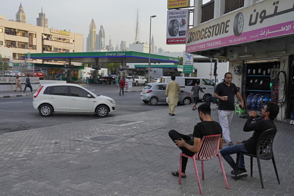 A man laughs while drinking tea as another passes holding karak in Dubai, United Arab Emirates, Wednesday, Aug. 24, 2022. Karak is the informal national drink of the United Arab Emirates, long priced at just 1 dirham, a bit less than 30 U.S. cents. But now, as supply chain shortages and Russia’s war on Ukraine lead to price spikes across the world, Dubai’s tea sellers are bumping up prices to 1.50 dirhams, or just over 40 cents. That’s a blow to migrant workers who depend on the drink as a daily ritual offering respite and fuel. (AP Photo/Jon Gambrell)