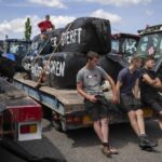 FILE- Protesting farmers talk at a blockade outside a distribution center for supermarket chain Aldi in the town of Drachten, northern Netherlands, Monday, July 4, 2022. Dutch lawmakers broke into their summer vacations Tuesday, Aug. 23, 2022 to debate the government’s contentious plans to slash nitrogen emissions that have sparked angry protests by farmers, after a senior minister cast doubt on the proposed timeline for cuts. (AP Photo/Peter Dejong, File)