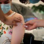 A healthcare worker administers the coronavirus disease (COVID-19) vaccine to a woman, amidst the spread of the SARS-CoV-2 variant Omicron in Johannesburg, South Africa, December 04, 2021. REUTERS/ Sumaya Hisham