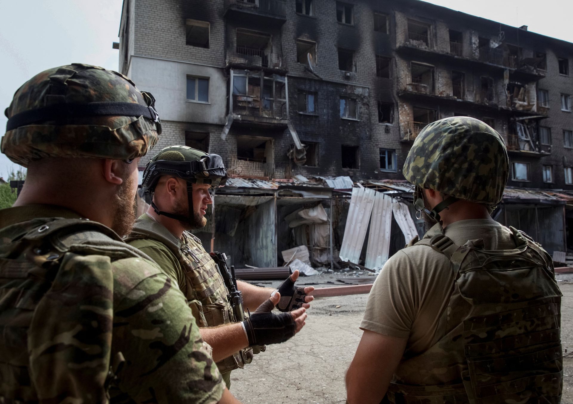 Ukrainian service members speak to each other in front of a residential building damaged by a Russian military strike, amid Russia’s attack on Ukraine, in the town of Siversk, Donetsk region, Ukraine August 20, 2022. REUTERS/Anna Kudriavtseva