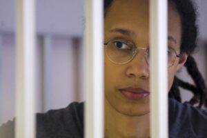 FILE – US Basketball player Brittney Griner looks through bars as she listens to the verdict standing in a cage in a courtroom in Khimki, outside Moscow, Russia, Thursday, Aug. 4, 2022. Lawyers for American basketball star Brittney Griner on Monday, Aug. 15, 2022 filed an appeal of her nine-year Russian prison sentence for drugs possession. Griner, a center for the Phoenix Mercury and a two-time Olympic gold medalist, was convicted on Aug. 4. She was arrested in February at Moscow’s Sheremetyevo Airport after vape canisters containing cannabis oil were found in her luggage. (Evgenia Novozhenina/Pool Photo via AP, File)