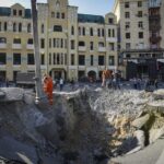 A view of a crater from a night Russian rocket attack, near to damaged buildings in downtown Kharkiv, Ukraine, Saturday, Aug. 27, 2022. (AP Photo/Andrii Marienko)