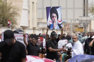 Supporters of Shiite cleric Muqtada al-Sadr with his poster gather during an open-air Friday prayers near the parliament building in Baghdad, Iraq, Friday, Aug. 26, 2022. Al-Sadr’s supporters continue their sit-in outside the parliament to demand early elections. (AP Photo/Hadi Mizban)