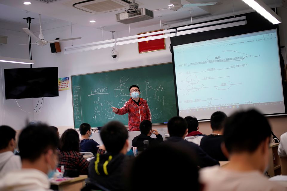 A teacher wearing a face mask teaches inside a classroom during a government-organised media tour at a high school as more students returned to campus following the coronavirus disease (COVID-19) outbreak, in Shanghai, China May 7, 2020. REUTERS/Aly Song