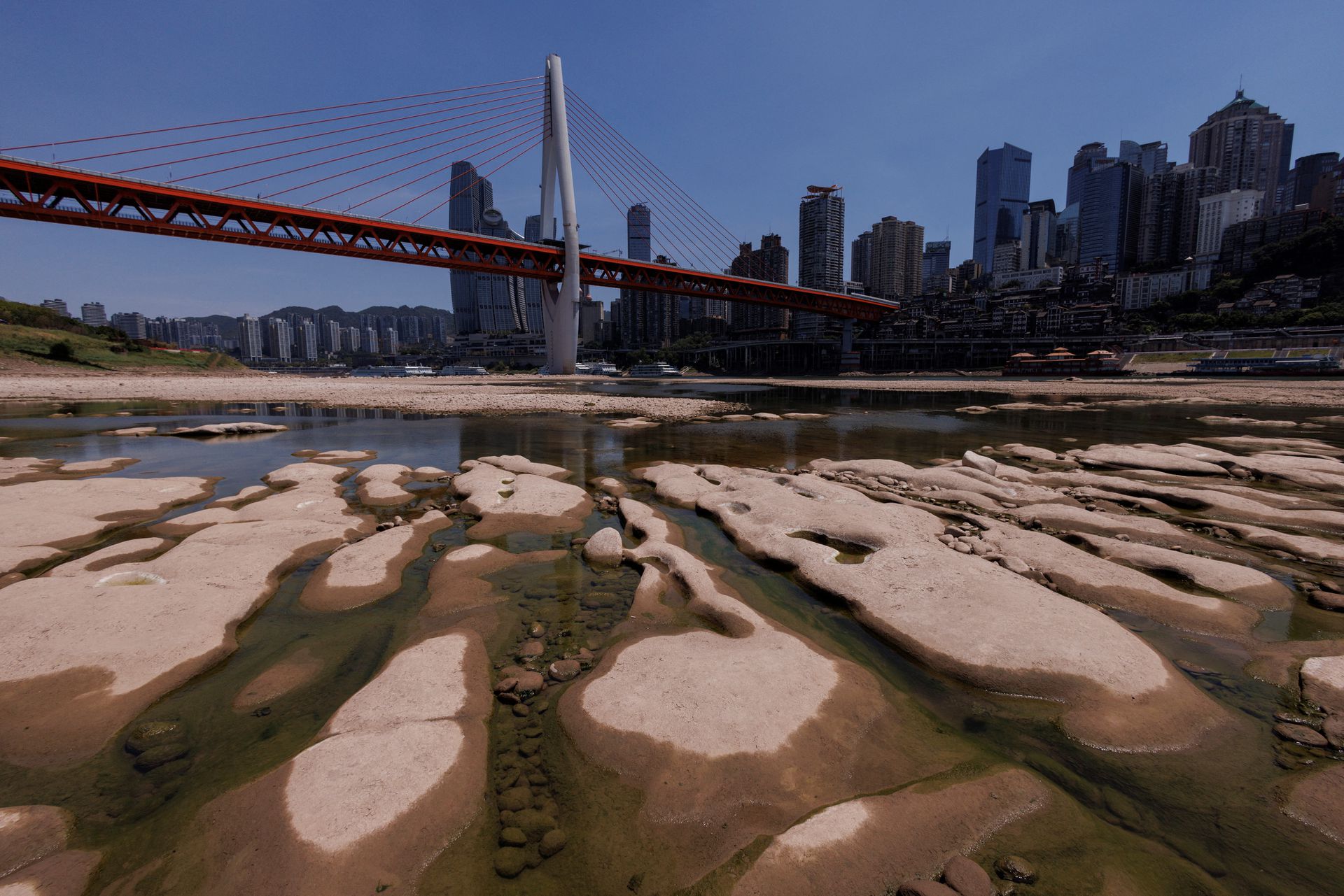 Qiansimen bridge runs over the dried-up riverbed of the Jialing river, a tributary of the Yangtze, that is approaching record-low water levels in Chongqing, China, August 18, 2022. REUTERS/Thomas Peter
