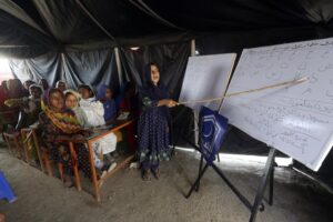 Flood affected children attend school organized by Islamic group Jamaat-e-Islami Pakistan, in Sukkur, Pakistan, Sunday, Sept. 4, 2022. Officials warned Sunday that more flooding was expected as Lake Manchar in southern Pakistan swelled from monsoon rains that began in mid-June and have killed nearly 1,300 people. (AP Photo/Fareed Khan)