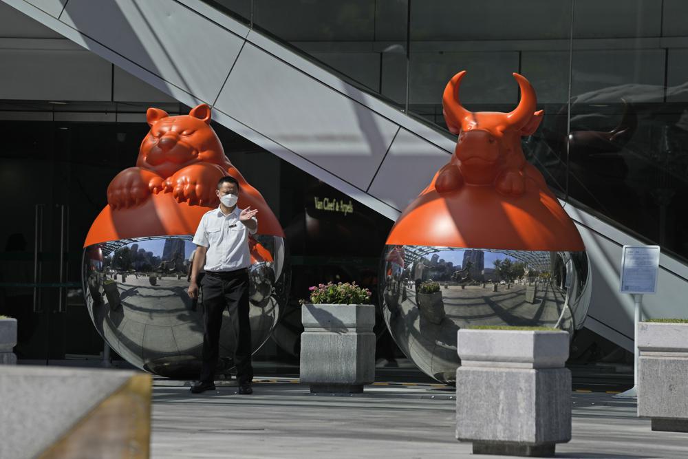 A security guard wearing mask directs traffic near art decor in Beijing, Thursday, Sept. 8, 2022. (AP Photo/Ng Han Guan)