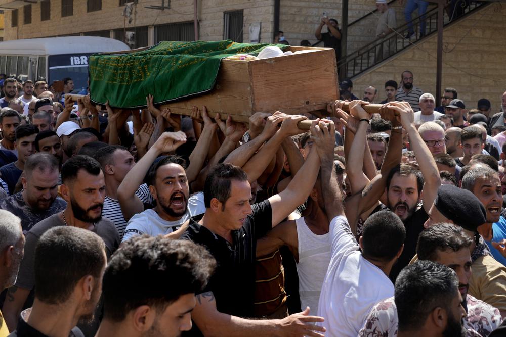 Mourners chant slogans as they carry the coffin of Palestinian Abdul-Al Omar Abdul-Al, 24, who was on a boat carrying migrants from Lebanon that sank in Syrian waters, during his funeral processions, in the Palestinian refugee camp of Nahr el-Bared near the northern city of Tripoli, Lebanon, Saturday, Sept. 24, 2022. Thousands of Palestinians held prayers in northern Lebanon Saturday for one of the scores of migrants who lost their lives this week when their boat sank off Syria’s coast. (AP Photo/Bilal Hussein)
