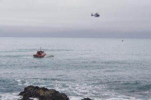A helicopter and a rescue boat search for survivors off the coast of Kaikoura, New Zealand, Saturday, Sept. 10, 2022. A boat in New Zealand collided with a whale and capsized. (AP Photo)