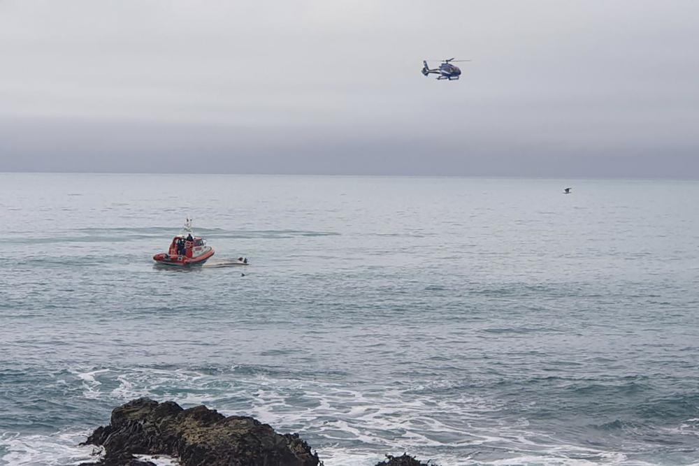 A helicopter and a rescue boat search for survivors off the coast of Kaikoura, New Zealand, Saturday, Sept. 10, 2022. A boat in New Zealand collided with a whale and capsized. (AP Photo)