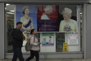 Posters of Queen Elizabeth II are displayed outside a pharmacy in the district of Southall in London, Tuesday, Sept. 13, 2022. In a church in a West London district known locally as Little India, a book of condolence for Queen Elizabeth II lies open. Five days after the monarch’s passing, few have signed their names. The congregation of 300 is made up largely of the South Asian diaspora, like the majority of the estimated 70,000 people living in the district of Southall, a community tucked away in London’s outer reaches of London and built on waves of migration that span 100 years. (AP Photo/Kin Cheung)