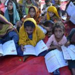 Victims of heavy flooding from monsoon rains attend school at a flood relief camp in Hyderabad, Pakistan, Saturday, Sept. 10, 2022. Months of heavy monsoon rains and flooding have killed over a 1000 people and affected 3.3 million in this South Asian nation while half a million people have become homeless. (AP Photo/Pervez Masih)