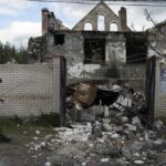 A Ukrainian serviceman from Dnipro-1 regiment walks past a damaged building in the retaken village of Shchurove, Ukraine, Sunday, Sept. 25, 2022. (AP Photo/Leo Correa)