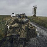 A Ukrainian soldier helps a wounded fellow soldier on the road in the freed territory in the Kharkiv region, Ukraine, Monday, Sept. 12, 2022. Ukrainian troops retook a wide swath of territory from Russia on Monday, pushing all the way back to the northeastern border in some places, and claimed to have captured many Russian soldiers as part of a lightning advance that forced Moscow to make a hasty retreat. (AP Photo/Kostiantyn Liberov)