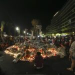 FILE – Flowers and tribute candles are laid out near the site of the truck attack in the French resort city of Nice, early Sunday, July 17, 2016. Eight people go on trial Monday Sept.5, 2022 in a special French terrorism court for alleged roles in helping the attacker who drove a truck into the Nice beachfront on Bastille Day 2016, killing 86 people. (AP Photo/Luca Bruno, File)