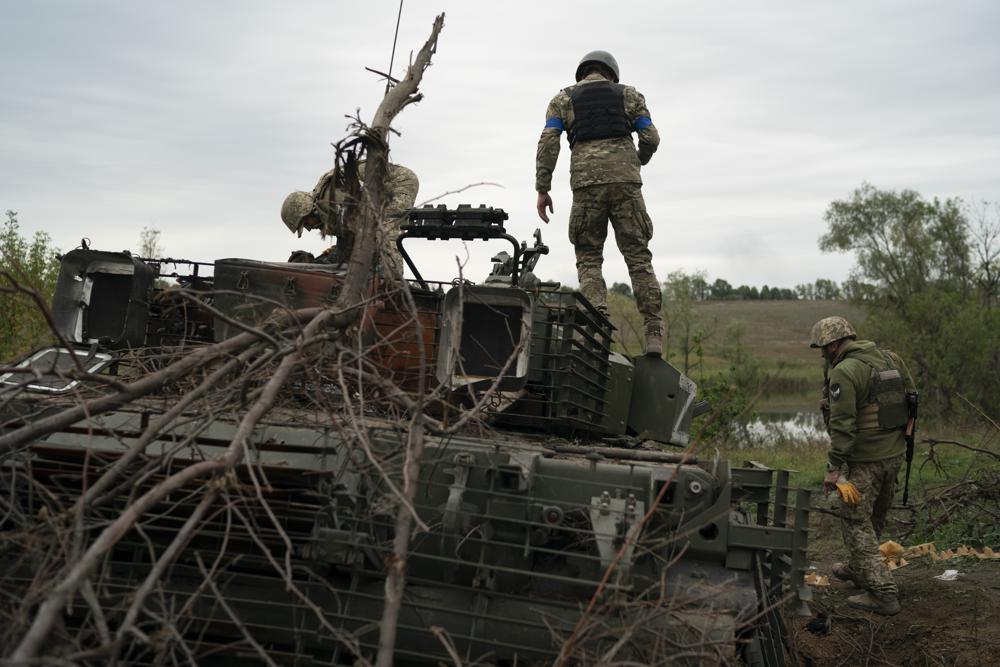 Ukrainian servicemen stand atop a destroyed Russian tank in a retaken area near the border with Russia in Kharkiv region, Ukraine, Saturday, Sept. 17, 2022. (AP Photo/Leo Correa)
