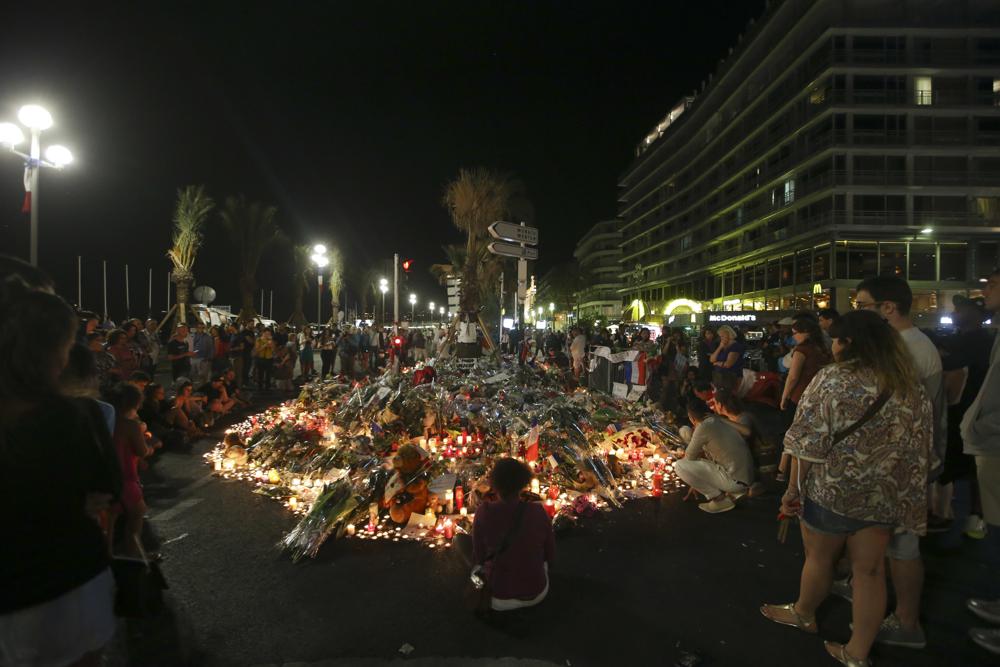 FILE – Flowers and tribute candles are laid out near the site of the truck attack in the French resort city of Nice, early Sunday, July 17, 2016. Eight people go on trial Monday Sept.5, 2022 in a special French terrorism court for alleged roles in helping the attacker who drove a truck into the Nice beachfront on Bastille Day 2016, killing 86 people. (AP Photo/Luca Bruno, File)