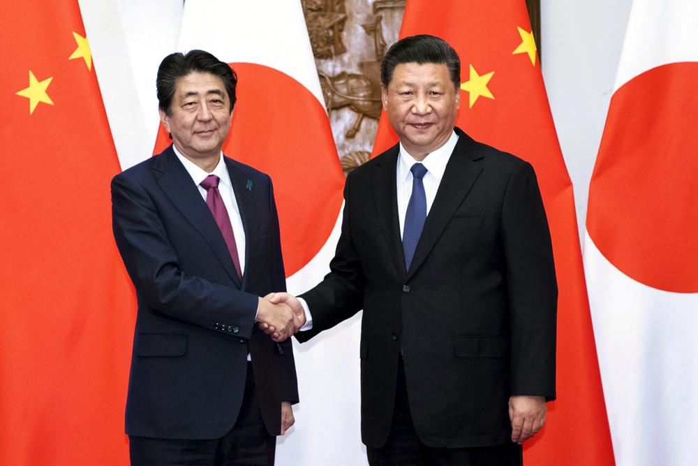 FILE – In this photo released by Xinhua News Agency, Japanese Prime Minister Shinzo Abe, left, shakes hands with Chinese President Xi Jinping as they pose for photographers before a meeting at the Diaoyutai State Guesthouse in Beijing on Oct. 26, 2018. Thursday, Sept. 29, 2022, marks the 50th anniversary of the historic communique that former Japanese Prime Minister Kakuei Tanaka signed with former Chinese Premier Zhou Enlai. (Li Tao/Xinhua via AP, File)