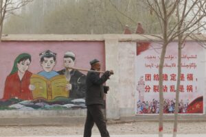 FILE – A farmer walks past government propaganda depicting ethnic minority residents reading the constitution with slogans which reads, “Unity Stability is fortune, Separatism and Turmoil is misfortune,” near Kashgar in northwestern China’s Xinjiang Uyghur Autonomous Region on March 19, 2021. China’s discriminatory detention of Uyghurs and other mostly Muslim ethnic groups in the western region of Xinjiang may constitute crimes against humanity, the U.N. human rights office said in a long-awaited report Wednesday, Aug. 31, 2022, which cited “serious” rights violations and patterns of torture in recent years. (AP Photo/Ng Han Guan, File)