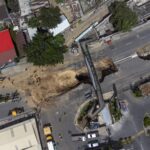View of a sinkhole on the main road in Villa Nueva, Guatemala, Tuesday, Sept. 27, 2022. Search efforts were underway for a mother and daughter who disappeared when their vehicle was swallowed by a massive sinkhole. (AP Photo/Moises Castillo)
