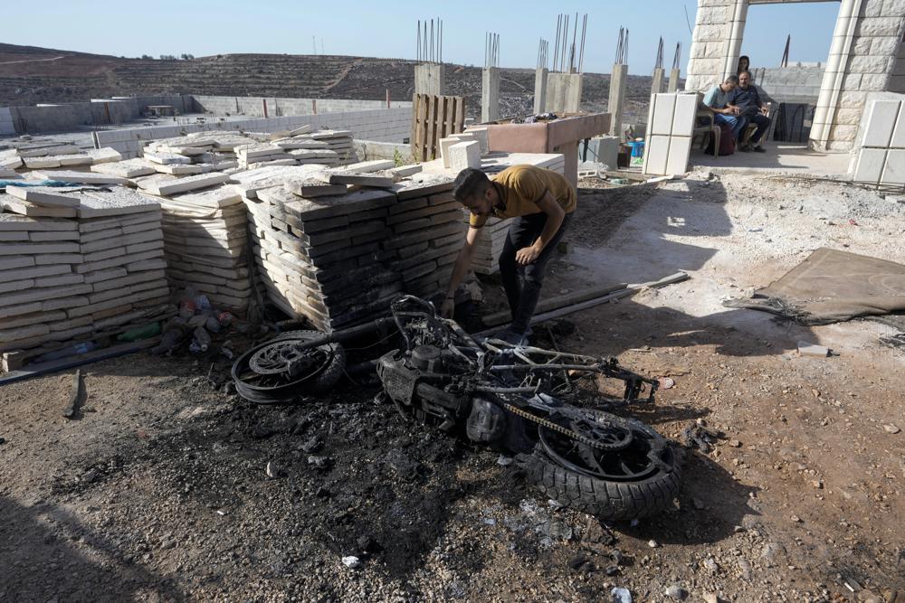 A Palestinian man points at a motorcycle in the northern West Bank, Sunday, Sept. 25, 2022. Israeli soldiers shot and killed a suspected Palestinian gunman during an arrest raid overnight in the northern West Bank, according to Israeli and Palestinian reports. The army said it spotted a group of armed men traveling in a car and on a motorcycle during an operation near the city of Nablus and opened fire. (AP Photo/Majdi Mohammed)