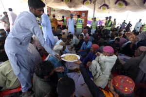 Victims of the unprecedented flooding from monsoon rains receive relief food organized by the Alkhidmat Foundation, in Jaffarabad, a district of Pakistan’s southwestern Baluchistan province, Monday, Sept. 5, 2022. The U.N. refugee agency rushed in more desperately needed aid Monday to flood-stricken Pakistan as the nation’s prime minister traveled to the south where rising waters of Lake Manchar pose a new threat. (AP Photo/Fareed Khan)