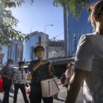 Commuters wearing face masks walk along a street in the central business district in Beijing, Thursday, Sept. 1, 2022. (AP Photo/Mark Schiefelbein)