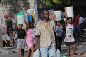 People carry containers with water amid water shortages due to daily protests against high gasoline prices and crime, and to stock up for Storm Fiona approaching in the Caribbean region, in Port-au-Prince, Haiti. September 17, 2022. REUTERS/Ralph Tedy Erol