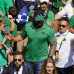 Former Notre Dame player Manti Te’o follows members of the Notre Dame football team walk through the crowd to the stadium before an NCAA college football game against California in South Bend, Ind., Saturday, Sept. 17, 2022. (AP Photo/Michael Conroy)