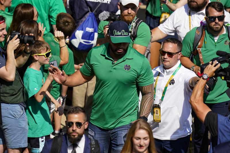 Former Notre Dame player Manti Te’o follows members of the Notre Dame football team walk through the crowd to the stadium before an NCAA college football game against California in South Bend, Ind., Saturday, Sept. 17, 2022. (AP Photo/Michael Conroy)