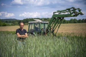 FILE – Ulf Allhoff-Cramer, farmer, stands in a rye field in front of his tractor in Detmold, Germany, on May 18, 2022. Environmentalists claimed a small legal victory Friday, Sept. 9, 2022, after a court in Germany said it would continue hearing a case brought by a local farmer seeking to force automaker Volkswagen to the sale of combustion engine vehicles. The plaintiff, Ulf Allhoff-Cramer, says drier soil and heavier rains due to climate change are harming his fields, cattle and commercial forests. (Lino Mirgeler/dpa via AP)