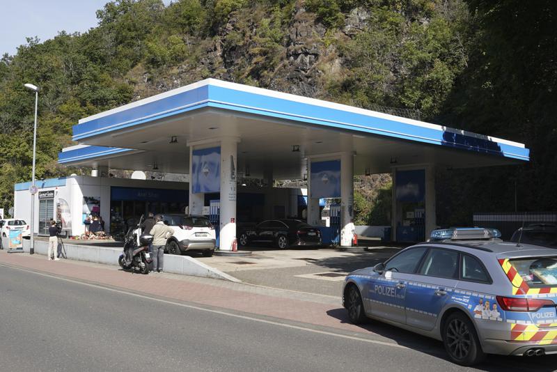FILE — Media and a police car stand in front of a gas station in Idar-Oberstein, Germany, Tuesday, Sept. 21, 2021. A German man was convicted of murder on Tuesday for fatally shooting a young gas station clerk a year ago following a dispute over face masks and given a life prison sentence. (Thomas Frey/dpa via AP, file)