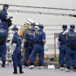 Police and firefighters inspect the scene where a man is reported to set himself on fire, near the Prime Minister’s Office in Tokyo, Wednesday, Sept. 21, 2022. The man was taken to a hospital Wednesday, in an apparent protest against a planned state funeral next week for the assassinated former leader Shinzo Abe, officials and media reports said.(Kyodo News via AP)