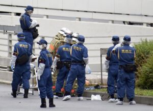 Police and firefighters inspect the scene where a man is reported to set himself on fire, near the Prime Minister’s Office in Tokyo, Wednesday, Sept. 21, 2022. The man was taken to a hospital Wednesday, in an apparent protest against a planned state funeral next week for the assassinated former leader Shinzo Abe, officials and media reports said.(Kyodo News via AP)