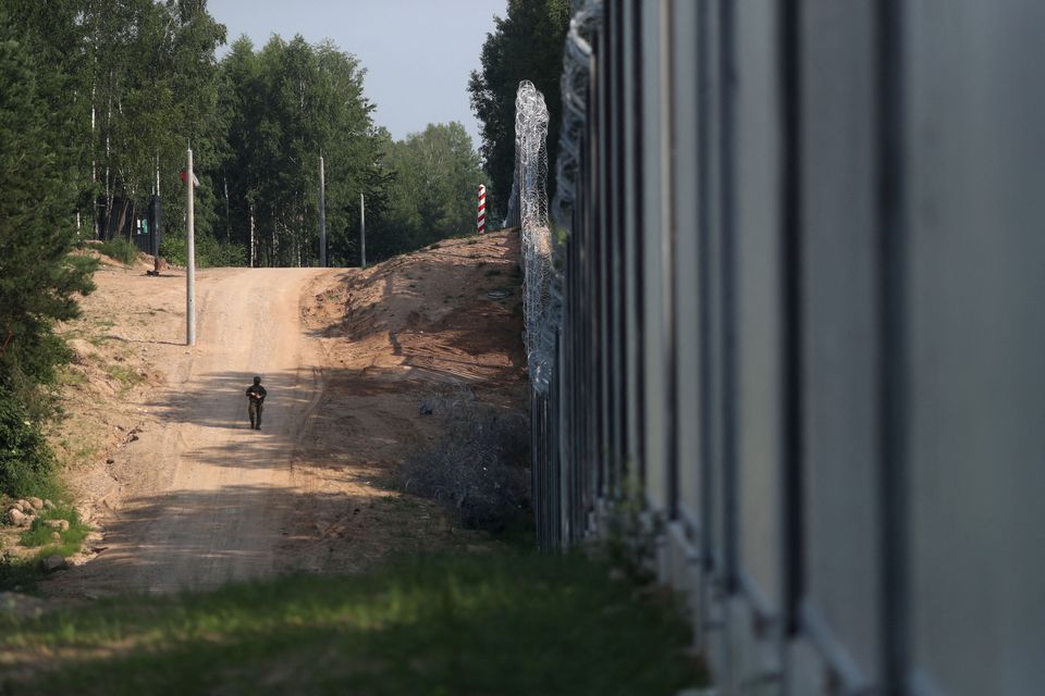A soldier patrols by the wall erected to prevent migrant crossings on the Polish-Belarusian border, near Kuznica, Poland June 30, 2022. REUTERS/Kacper Pempel