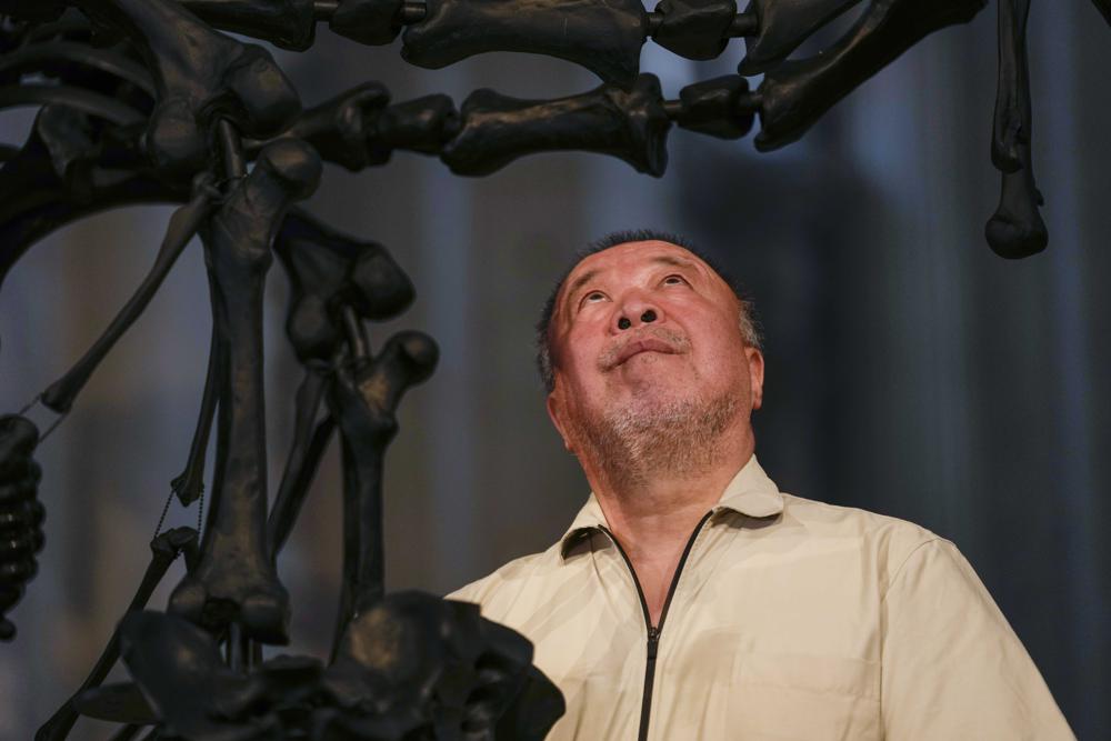 Chinese artist Ai Weiwei poses in front of his unveil glass body of work ‘La Commedia Umana’ a huge hanging glass sculpture otherwise referred to as a ‘chandelier’ at the San Giorgio deconsecrated church in Venice, Italy, Friday, Aug. 26, 2022. Chinese artist Ai Weiwei lampoons the surveillance culture and social media with his first ever glass sculpture, made on the Venetian island of Murano, that stands as a warning to the world: “Memento Mori,” or Latin for “Remember You Must Die.” (AP Photo/Luca Bruno)