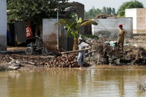A man clears rubble of his makeshift stall amid flood water, following rains and floods during the monsoon season in Nowshera, Pakistan September 2, 2022. REUTERS/Fayaz Aziz