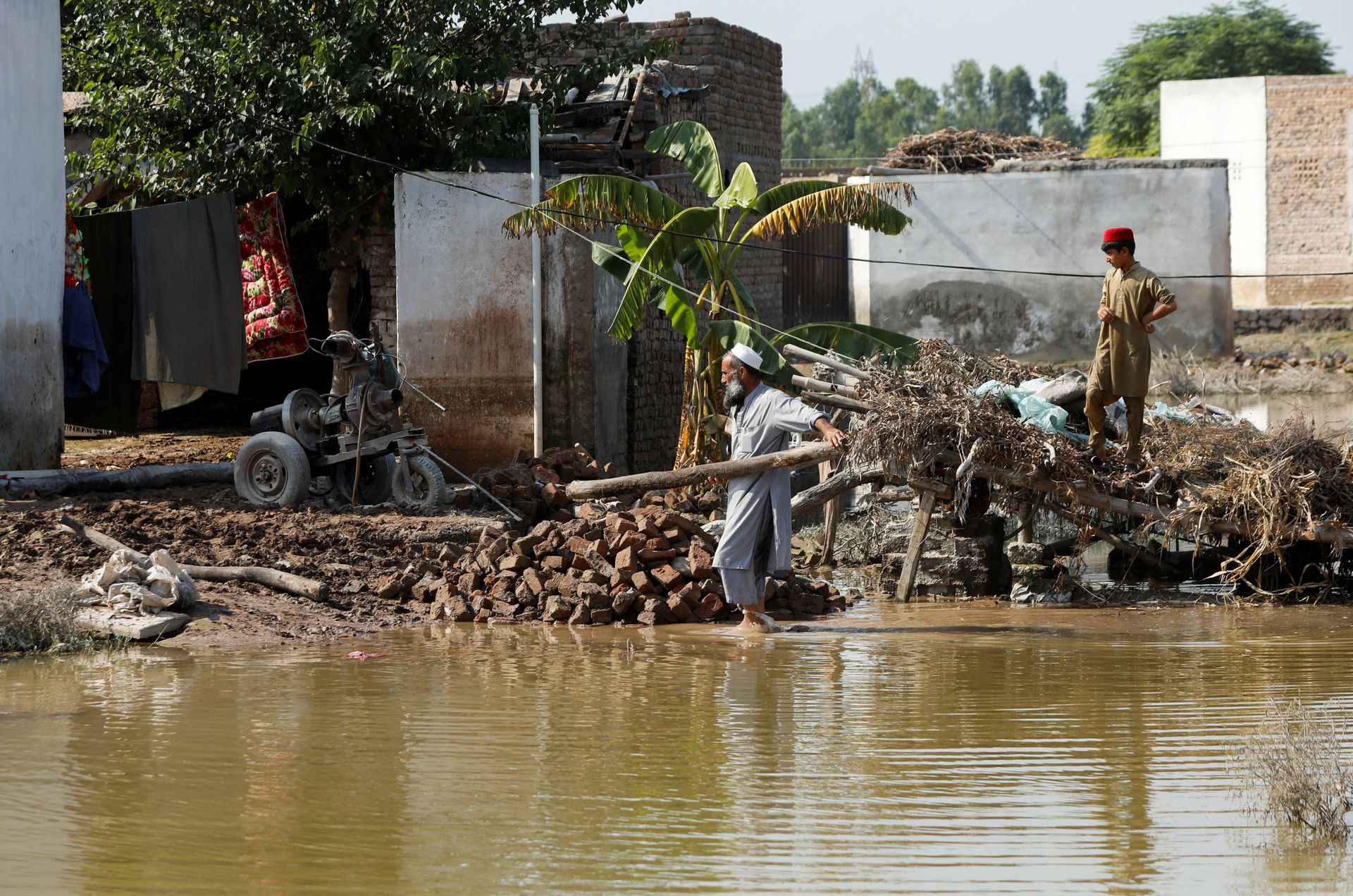 A man clears rubble of his makeshift stall amid flood water, following rains and floods during the monsoon season in Nowshera, Pakistan September 2, 2022. REUTERS/Fayaz Aziz