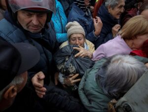 A local resident carries away a bag from a car distributing humanitarian aid, as Russia’s attack on Ukraine continues, in the town of Balakliia, recently liberated by Ukrainian Armed Forces, in Kharkiv region, Ukraine September 13, 2022. REUTERS/Gleb Garanich