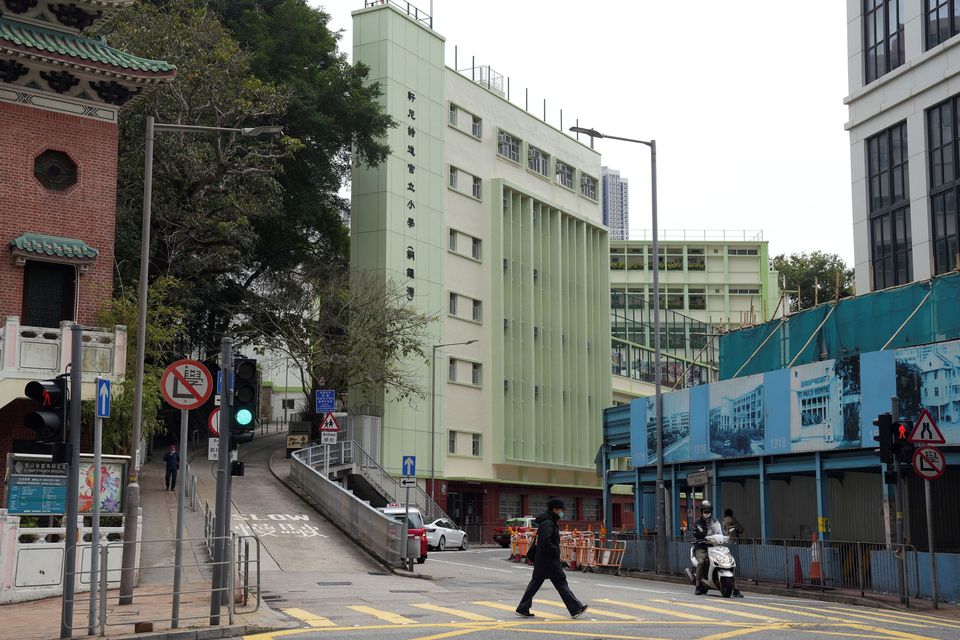 A pedestrian wearing a face mask following the coronavirus disease (COVID-19) outbreak, walks past a primary school in Hong Kong, China February 23, 2022. REUTERS/Lam Yik
