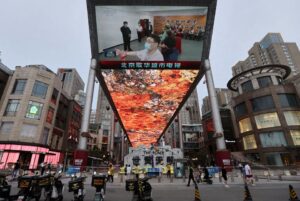 A giant screen shows news footage of Chinese President Xi Jinping visiting Xinjiang Uyghur Autonomous Region, at a shopping centre, in Beijing, China, July 15, 2022. REUTERS/Tingshu Wang/File Photo